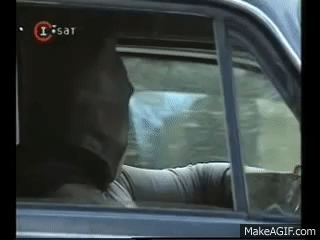 El GIF muestra a una persona dentro de un automóvil, disfrazada de batman, mientras aplaude adentro de un auto. El video tiene una marca de agua de I-Sat, un canal de televisión, en la esquina superior izquierda, lo que indica que es una escena posiblemente de una película o programa transmitido en ese canal.